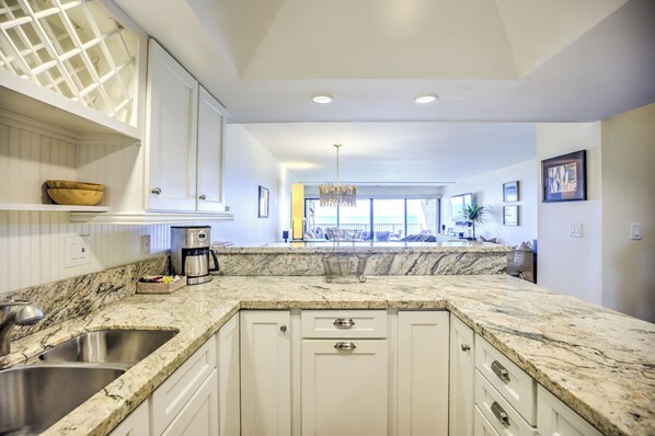 A kitchen with white cabinets, a marble countertop, and a built-in sink.