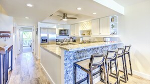 A spacious kitchen with a large island, bar stools, and modern appliances. - Oceanfront Boho Chic Townhouse (Key Colony Beach)