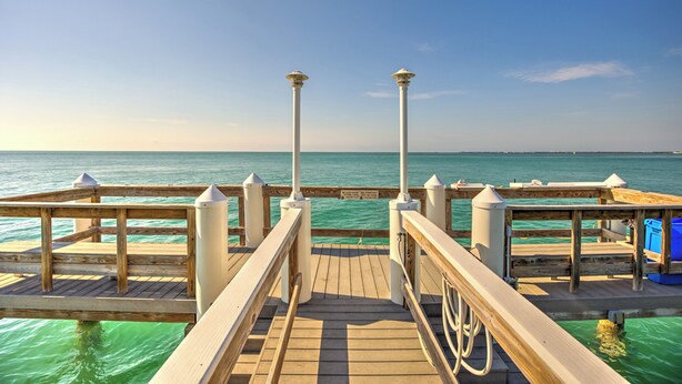 A wooden pier leading to a dock with a clear view of the turquoise sea. - Oceanfront Boho Chic Townhouse (Key Colony Beach)