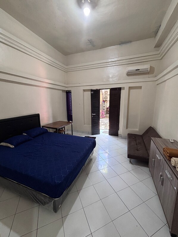A bedroom with a bed, a small table, a sofa, and a cabinet.