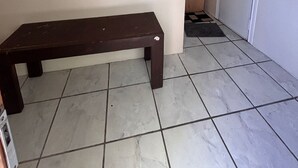 A room with a wooden bench, tiled floor, a door, and an air conditioning unit on the wall. - Agung Residence (Denpasar)