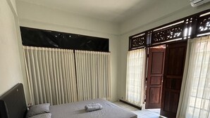 A bedroom with a bed, curtains, a ceiling fan, and a door. - Agung Residence (Denpasar)