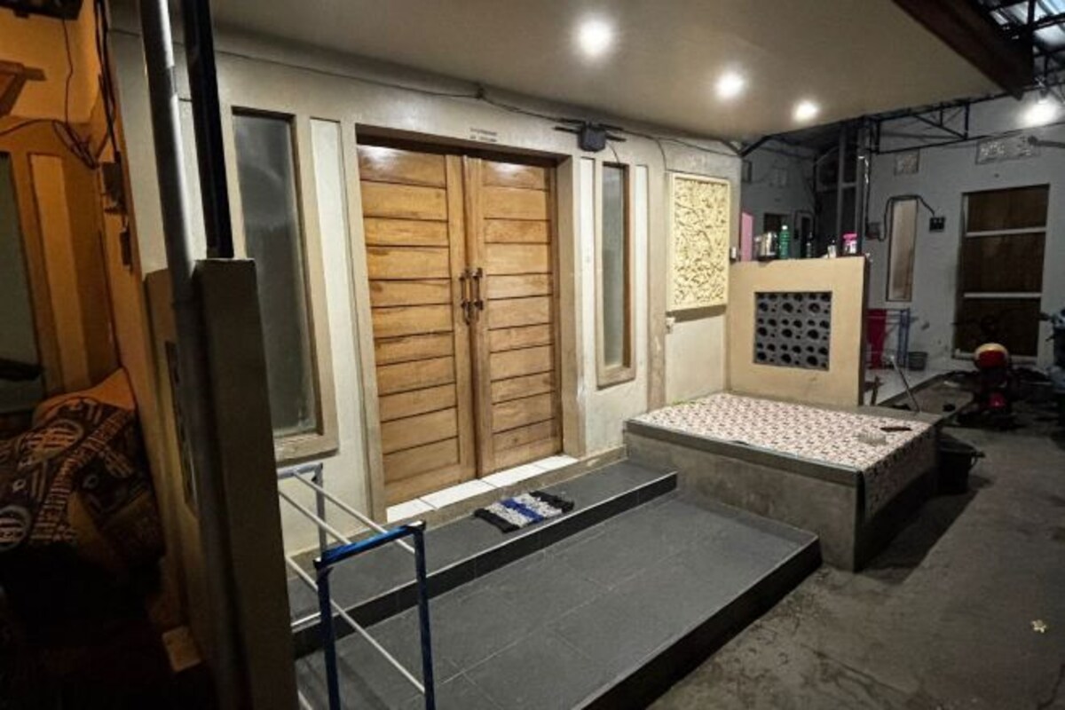 A room with a large wooden door, a small window, and a patterned bench.