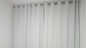 Habitació d'hotel amb un llit, un llençol vermell, un coixí blanc i una tovallola enrotllada sobre el llit.
