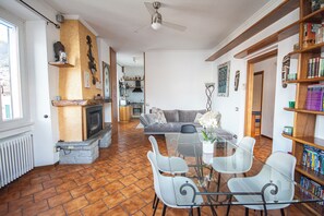 Una sala de estar con chimenea, una mesa de comedor con sillas, un sofá y una estantería.