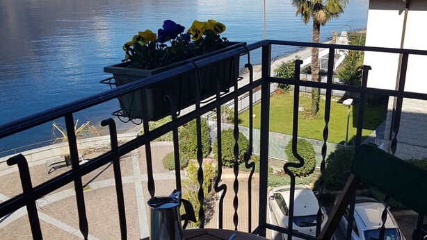 A balcony with a view of a lake and mountains, a table with a pitcher and cups, and a planter with flowers. - Emi s House (Lezzeno)