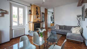 A living room with a fireplace, a sofa, a glass coffee table, and a ceiling fan. - Emi s House (Lezzeno)