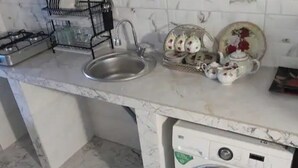 Une cuisine équipée d’un évier, d’un égouttoir, d’une cuisinière à gaz et d’un lave-linge.