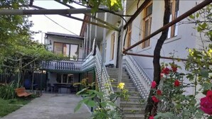 Une cour intérieure avec un escalier menant à un bâtiment, le tout entouré de verdure et de fleurs.