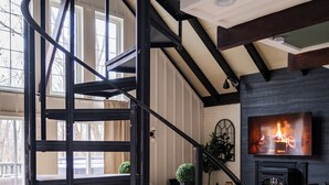 Un interior moderno con una escalera de caracol, una chimenea y una pantalla de televisión grande.
