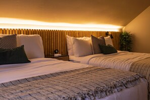 Two beds with complementary bedding, a bedside table, and a lamp.