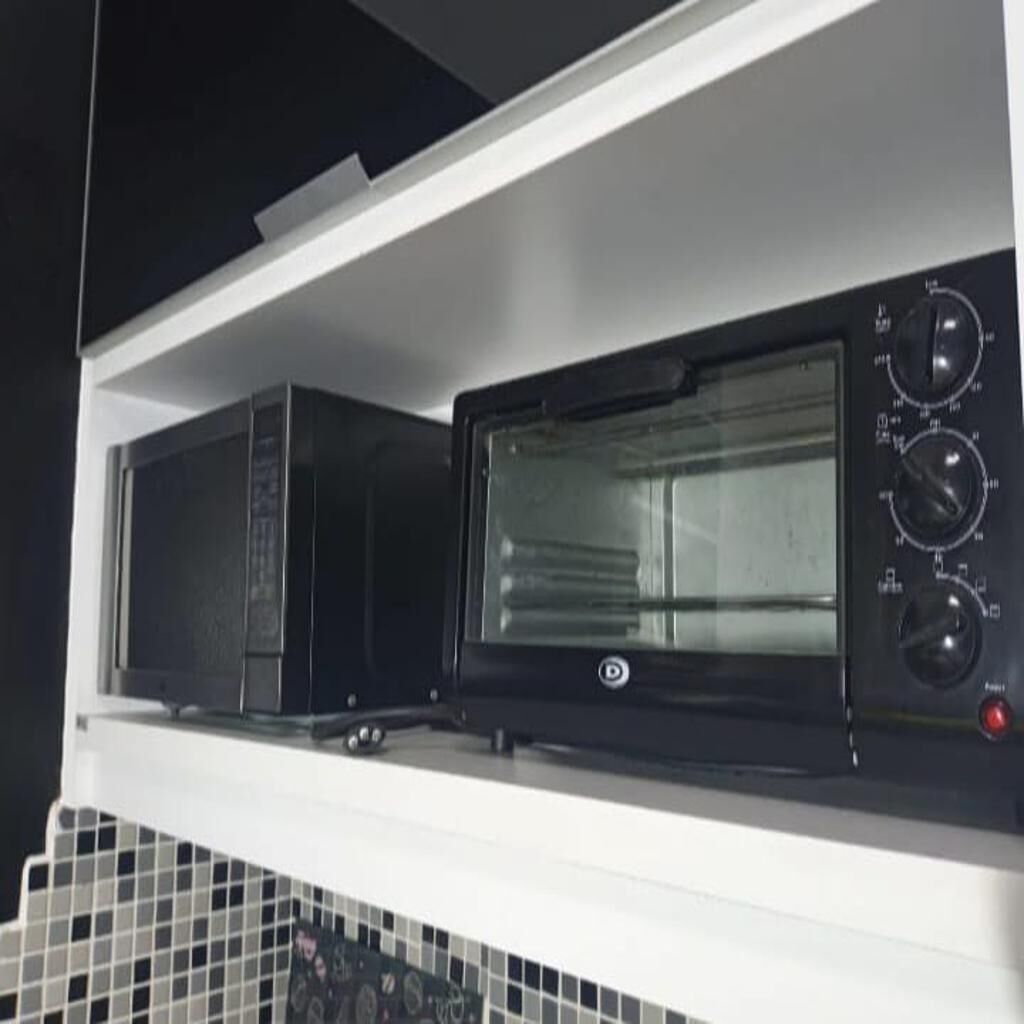 A kitchen with a microwave and oven on a white shelf.