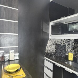 Compact kitchen with modern design, featuring a stainless steel sink, microwave oven, and chalkboard wall.
