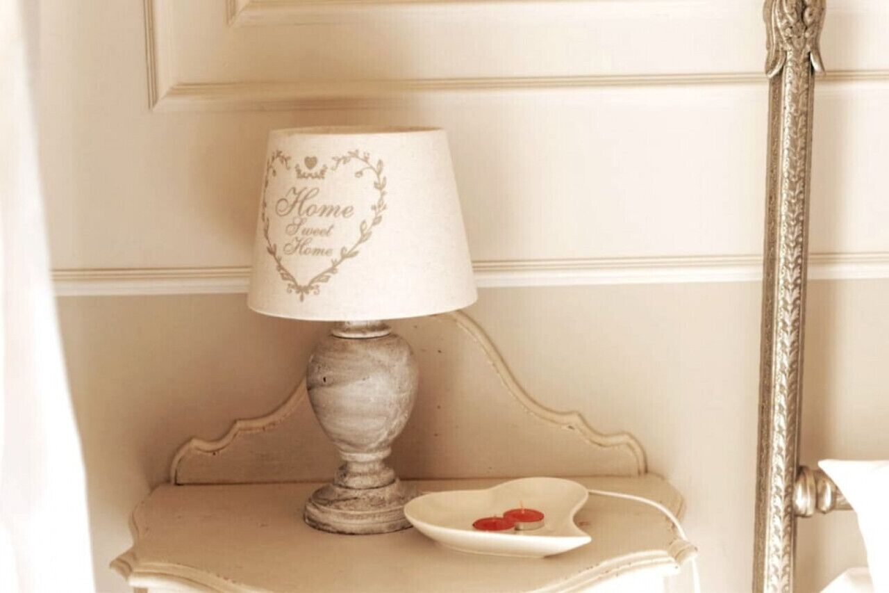 Een lamp in vintage stijl met een hartvormig ontwerp op de lampenkap, geplaatst op een klein tafeltje met een decoratief bord ernaast.