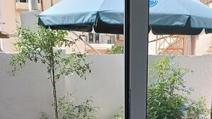 A balcony with a table and chairs, potted plants, and a view of the surrounding buildings. - Dimitri's Cosy Home in Nea Ionia with wifi,a/c, kitchen and sunny yard  (Nea Ionia)