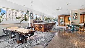 A modern hotel lobby with a bar area, seating arrangements, and large windows offering city views. - Private studio partial ocean/city view, no resort or cleaning fee, with parking! (Honolulu)