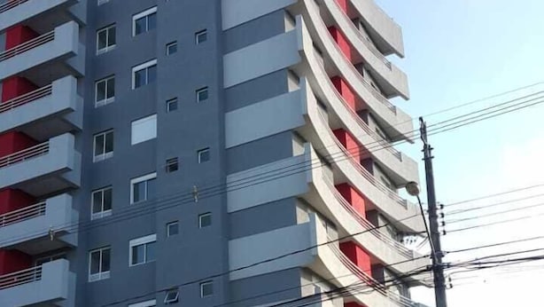Un immeuble à plusieurs étages doté de balcons, d’une entrée sécurisée et surplombant un ciel dégagé.