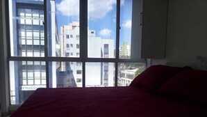 Une chambre avec un lit et une grande fenêtre.