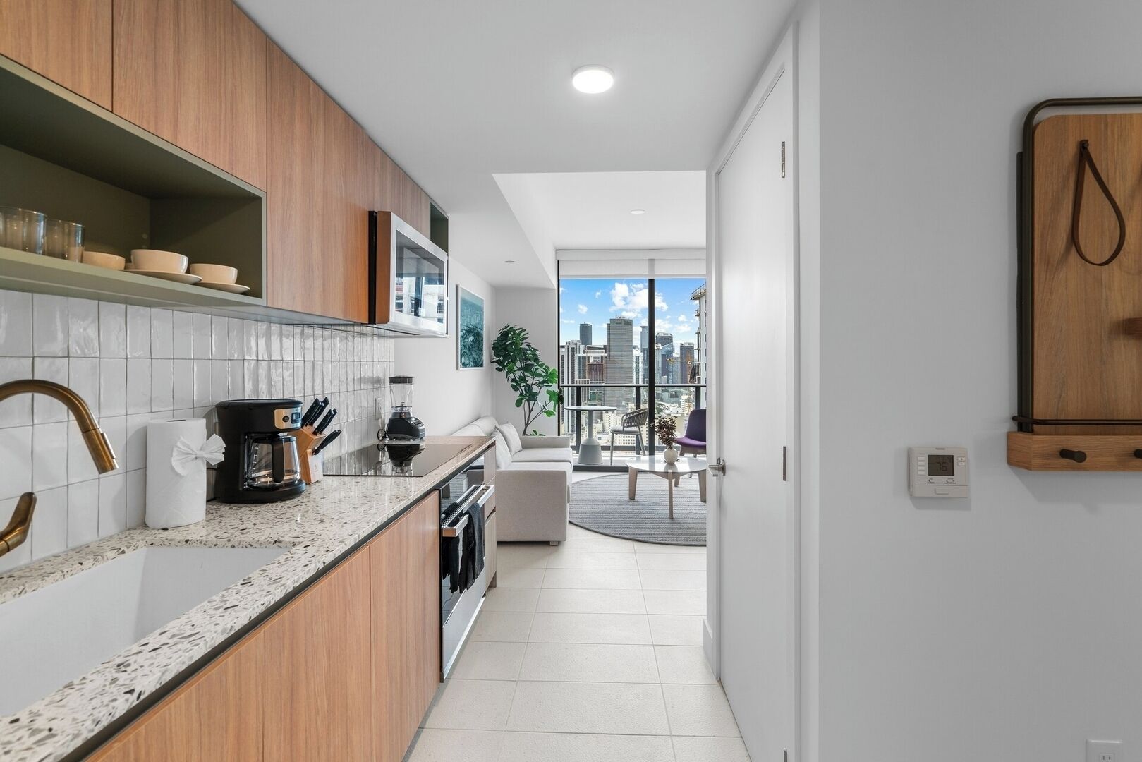 A modern kitchen with wooden cabinets, a granite countertop, and a city view through large windows.
