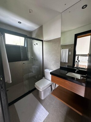 Chuveiro, secador de cabelo, toalhas de banho, papel higiênico