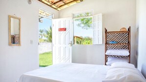 A bedroom with a bed, a wooden ladder, and a view of the outdoors.