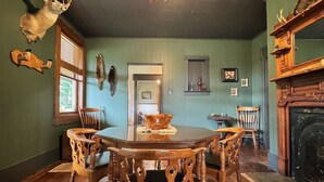A dining room with a wooden table and chairs, a ceiling fan, and a fireplace.