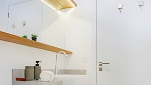 A modern bathroom with a white sink, a mirror, and a toilet. - HomyCO - Conforto na esqui praia (Niteroi)