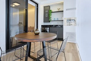 A modern kitchen with a round wooden table, black chairs, and a vase. - HomyCO - Conforto na esqui praia (Niteroi)