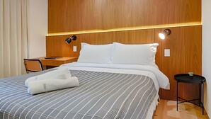 A hotel room with a large bed, a desk, and two wall-mounted lamps. - HomyCO - Conforto na esqui praia (Niteroi)