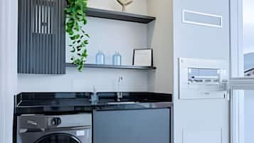 Uma cozinha moderna com máquina de lavar e secar integradas, bancada preta e janela com vista.