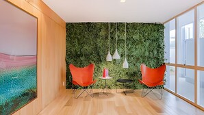 A modern office space with a green wall, two red chairs, a small table, and pendant lights. - HomyCO - Conforto na esqui praia (Niteroi)
