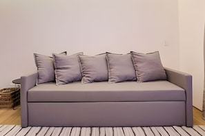 A grey sofa with five cushions against a plain wall and a striped rug. - HomyCO - Conforto na esqui praia (Niteroi)