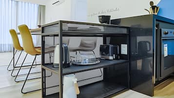 A modern kitchen with a glass-top island, a coffee machine, and a kettle.