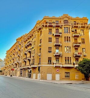 A multi-story building with balconies, a street in front, and a clear sky. - Dior Hotel (Cairo)