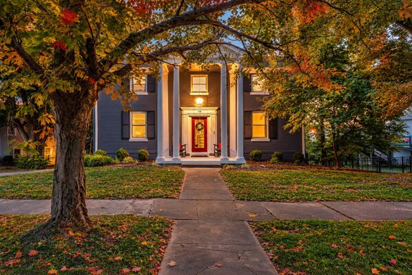 A two-story house with a front porch, columns, and a well-maintained lawn.