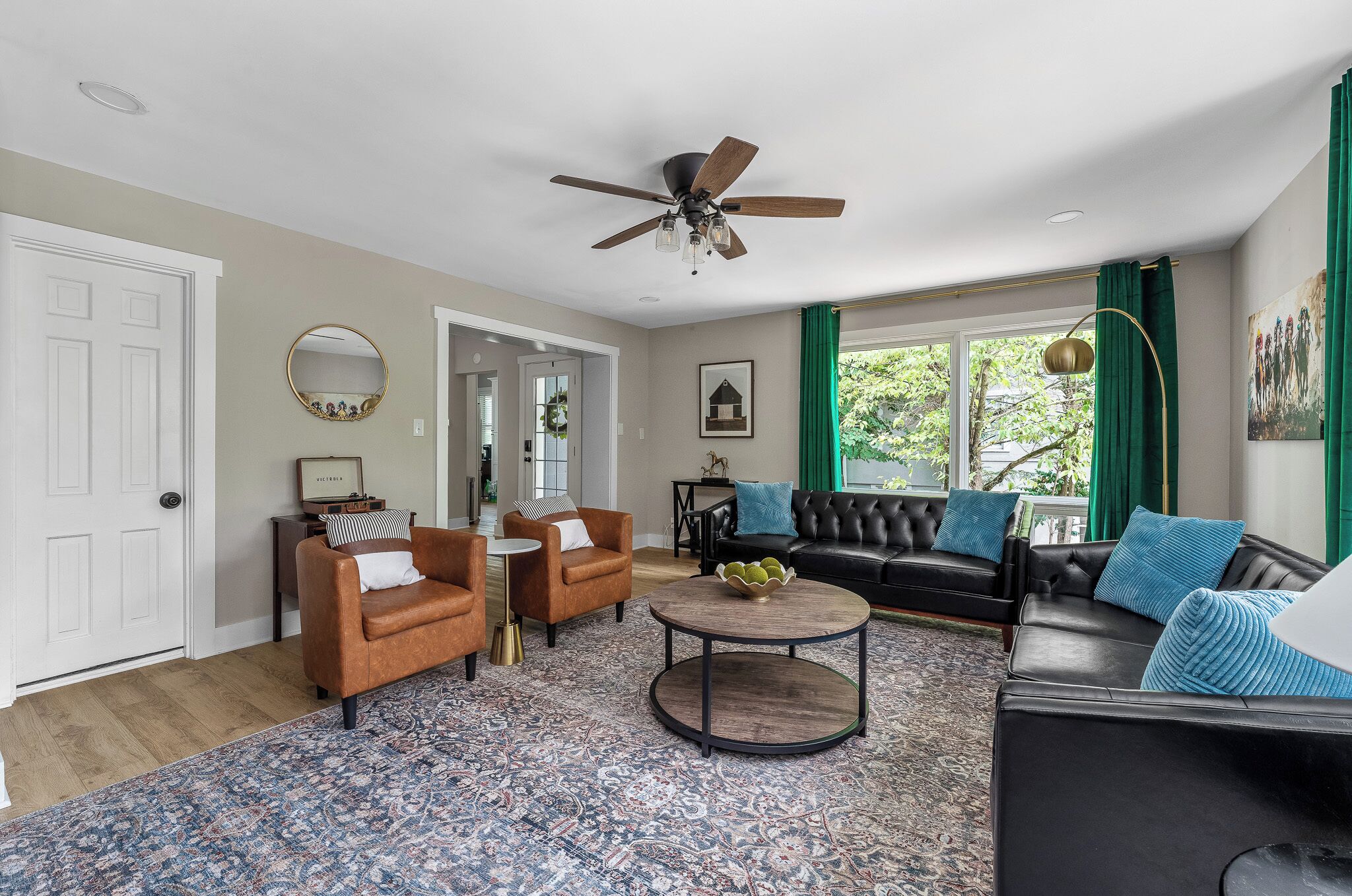 A living room with a ceiling fan, two leather sofas, a coffee table, and a patterned rug.