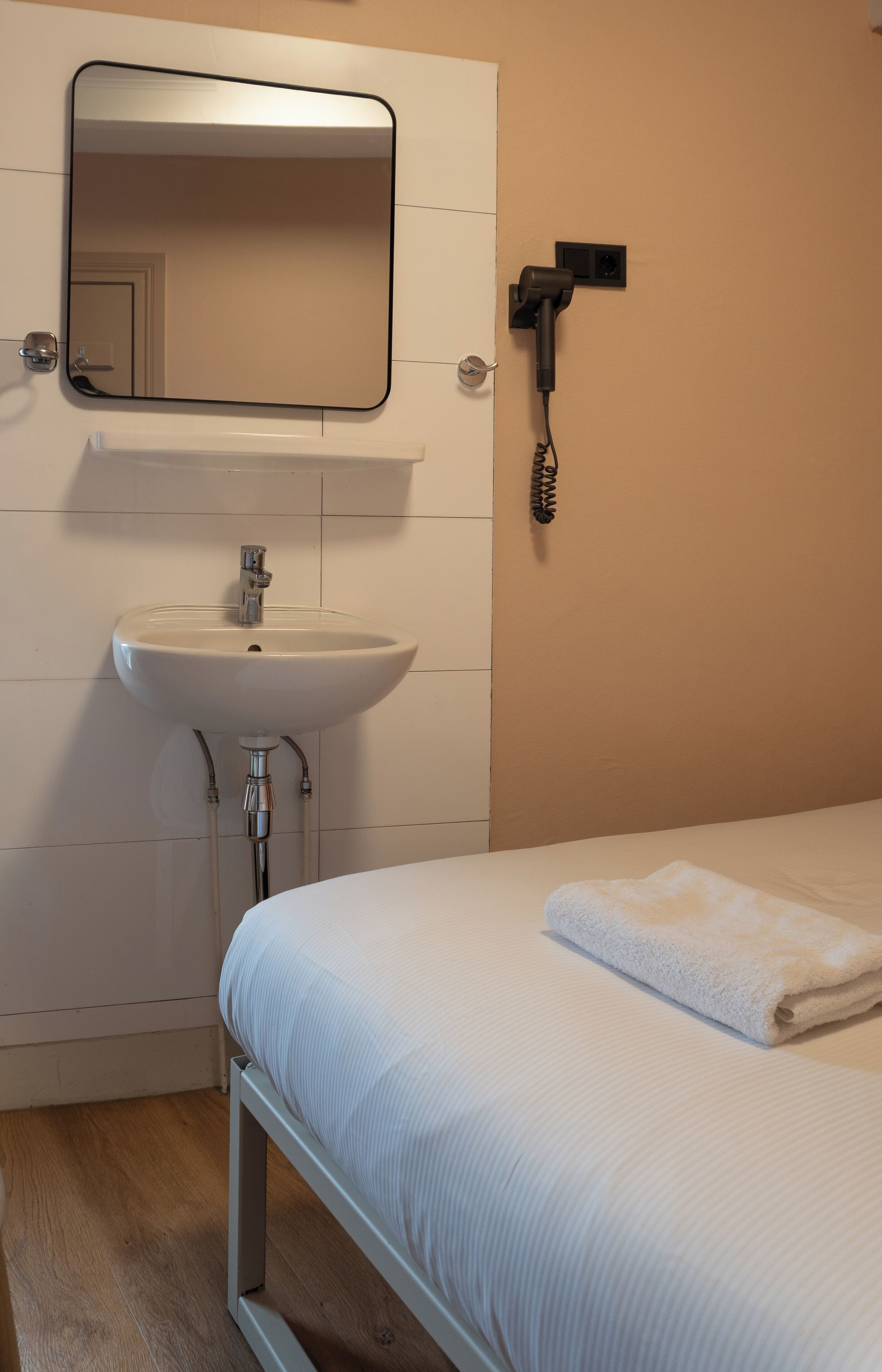 A bathroom with a sink, mirror, and hairdryer.