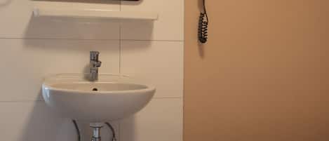 A bathroom with a sink, mirror, and hairdryer.