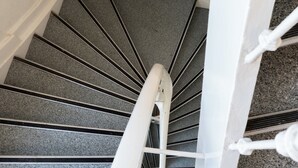 A spiral staircase with a handrail, carpeted steps, and a wooden finish at the bottom. - CS Hotel (Amsterdam)