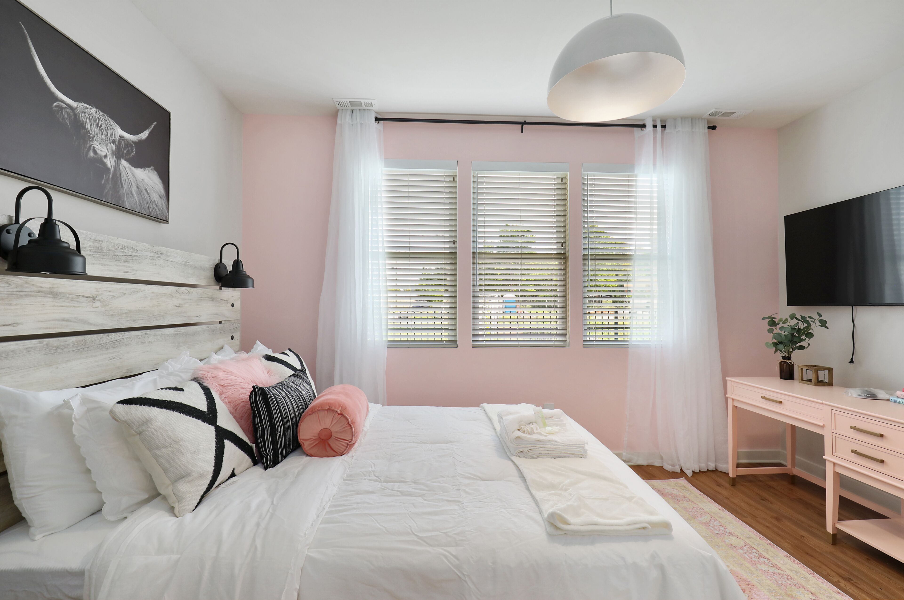 A bedroom with a bed, bedside table, and a desk with a chair.