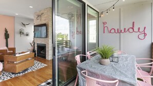 Un salon moderne doté d’un mur en verre, d’une cheminée et d’un coin repas avec des chaises roses et une table.