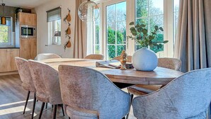 Un comedor con una mesa de madera, sillas tapizadas de gris y un jarrón blanco con plantas verdes.