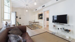 A modern living room with a brown leather sofa, a glass coffee table, and a mounted TV.
