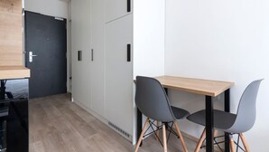 Una habitación moderna con una mesa de madera y dos sillas, un armario y una puerta.