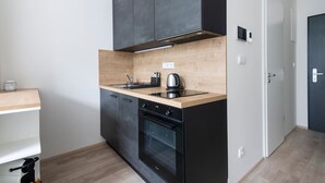 Una cocina compacta con un horno negro, un microondas integrado y una encimera de madera.
