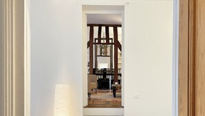 A staircase leading to a dining area with a chandelier, wooden beams, and a patterned rug.