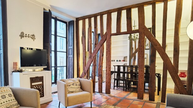 A living room with a TV, sofas, a coffee table, and a wooden beam structure.