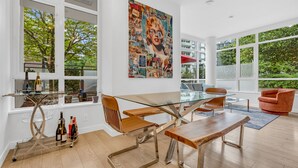 Un espace repas moderne avec une table en verre, des chaises en bois et une grande affiche accrochée au mur.
