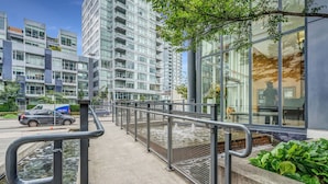 Un bâtiment urbain moderne doté d’une façade en verre, d’une promenade piétonne et d’un petit élément décoratif aquatique.