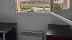 Una habitación con un ventanal grande, un radiador y un escritorio.